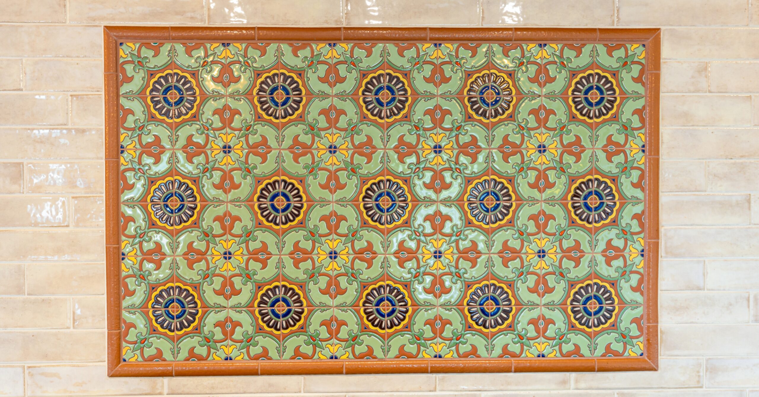 Decorative Spanish-inspired ceramic tile backsplash feature wall in a Mission-style kitchen remodel with warm earth tones and handcrafted detailing.