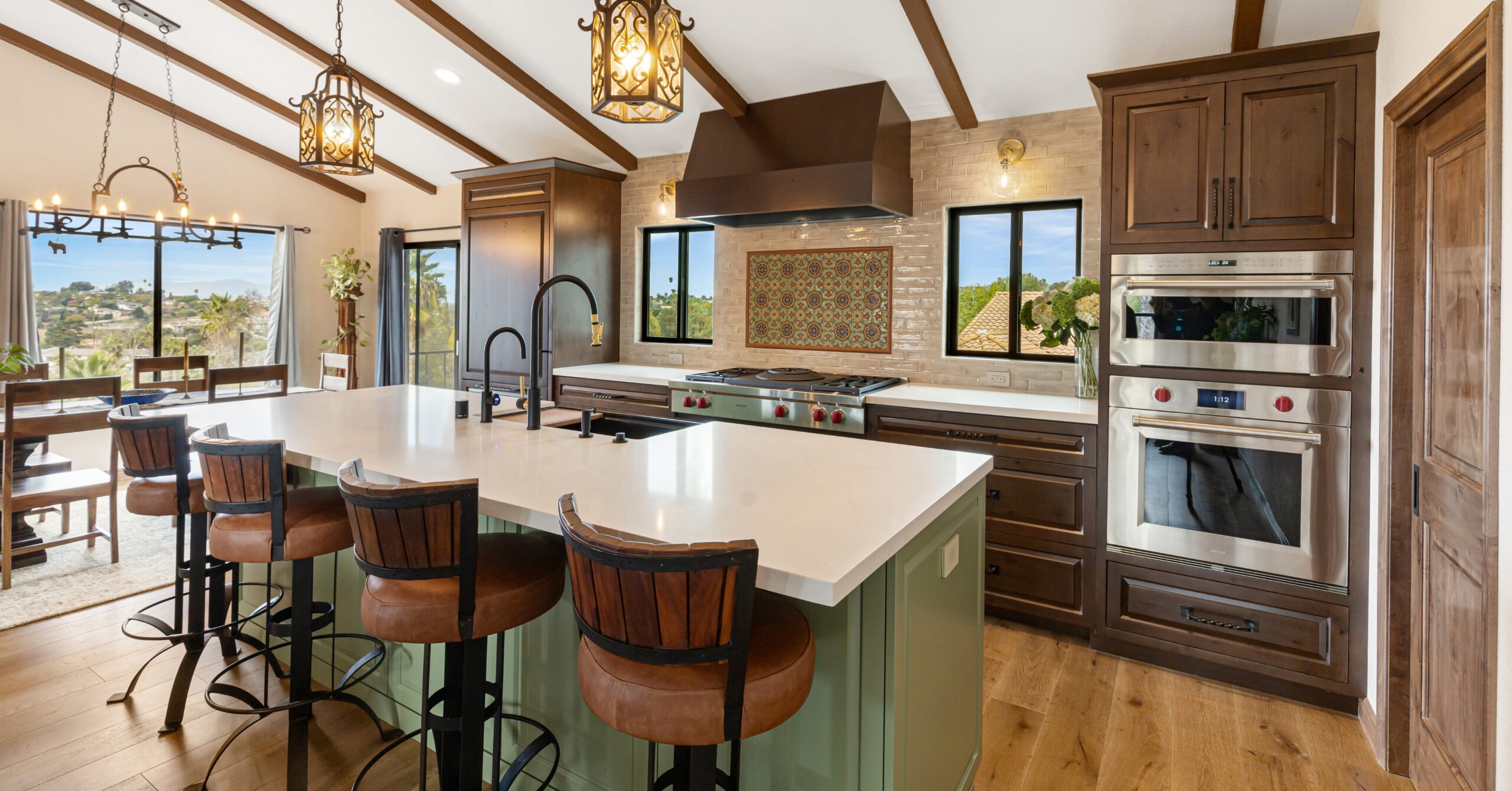 Open-concept kitchen renovation in Vista CA designed to eliminate a cramped layout with a large gathering island, custom cabinetry, vaulted ceilings, Wolf appliances, and seamless connection to adjacent living spaces.