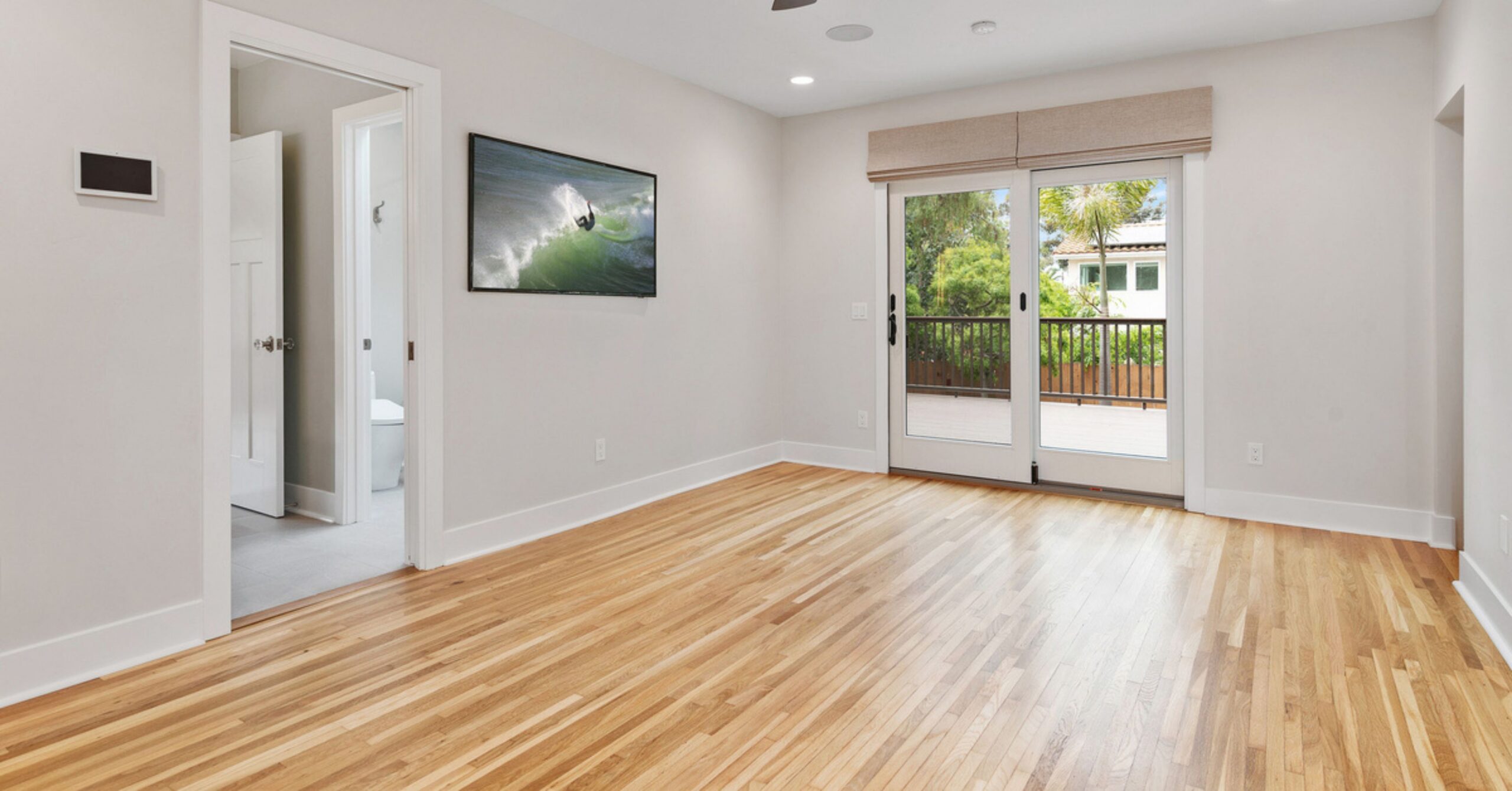 New primary bedroom in a remodeled South Park Craftsman home with hardwood flooring, abundant natural light, and sliding glass doors leading to a private outdoor deck.