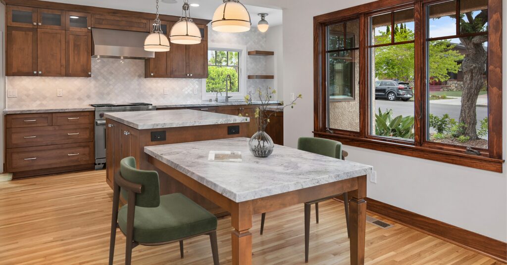 Open-concept Craftsman kitchen in a South Park whole-home remodel featuring custom wood cabinetry, marble island and dining table, restored wood windows, and an improved layout designed for gathering and everyday living.