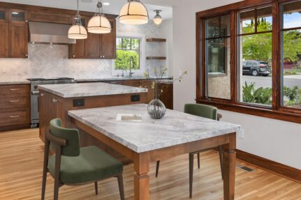 Open-concept Craftsman kitchen in a South Park whole-home remodel featuring custom wood cabinetry, marble island and dining table, restored wood windows, and an improved layout designed for gathering and everyday living.
