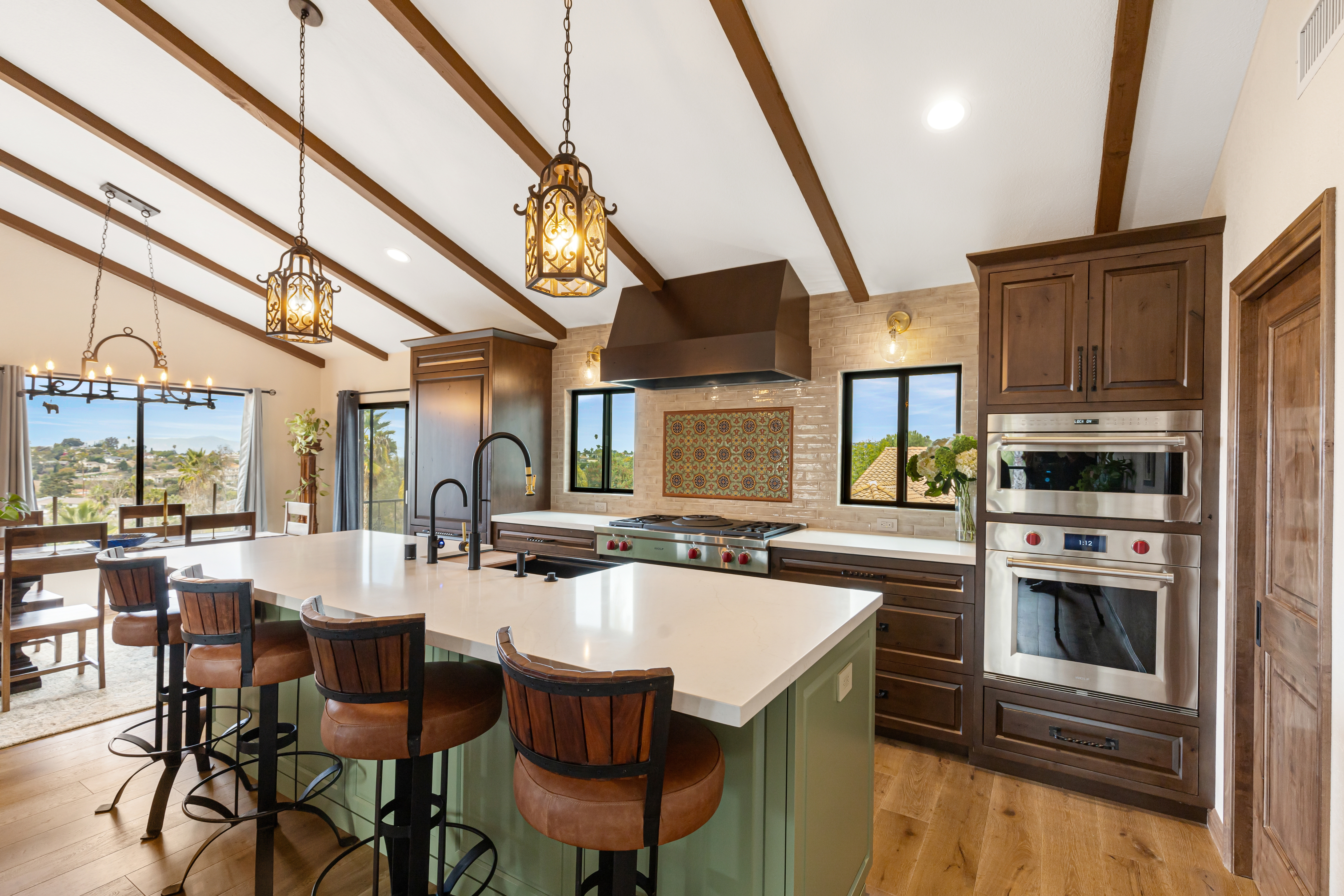 Modern Mission kitchen with green island seating, wood cabinets, pendant lights, range and wall ovens.