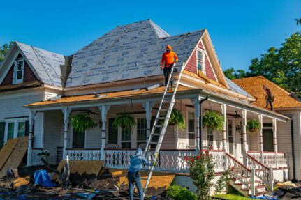 Licensed roofing contractors replacing the roof on a historic home during a permitted exterior renovation project.
