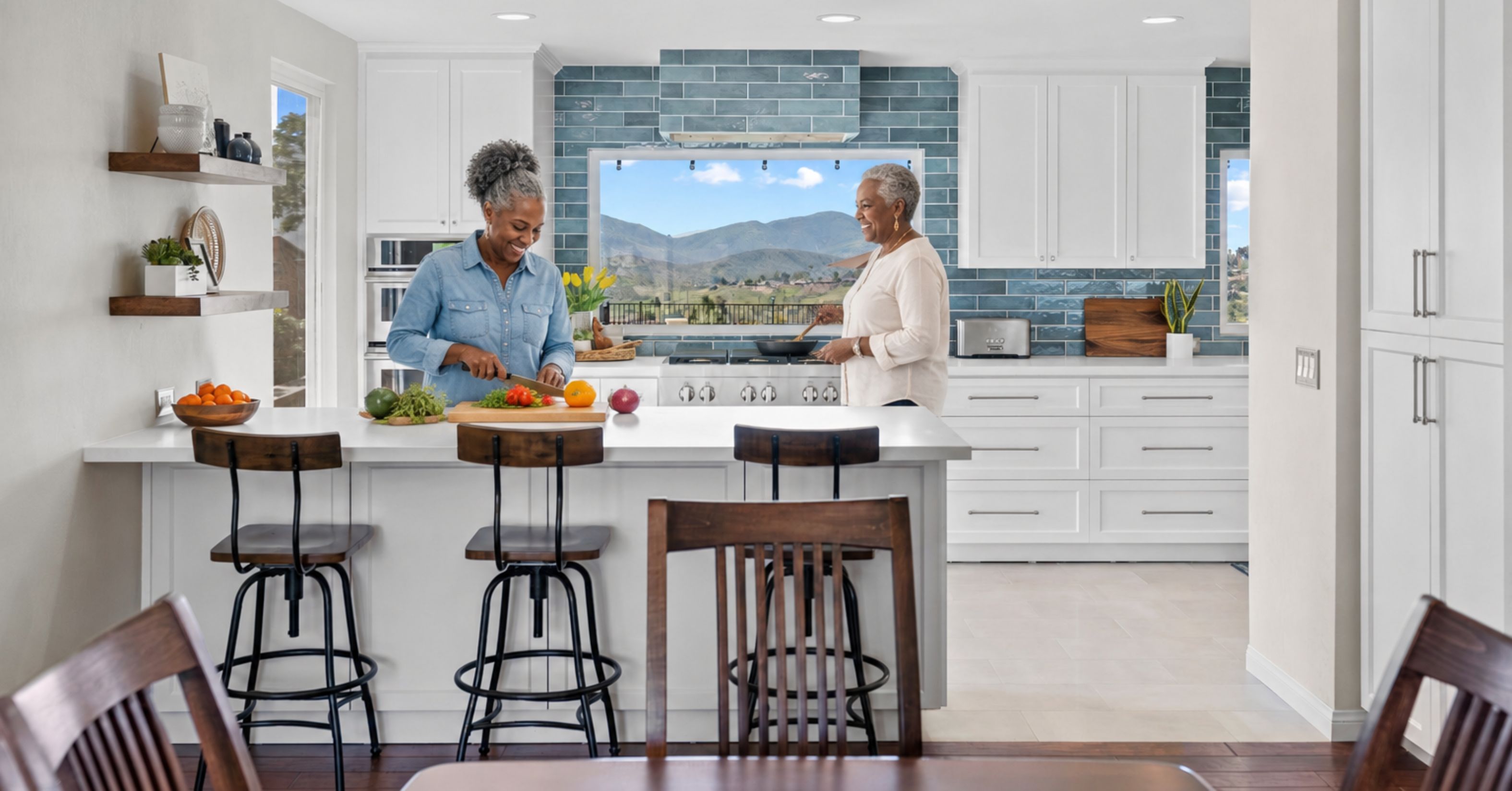 Two women preparing food together in a bright open-concept kitchen with a large island, wide walkways, and accessible layout for aging in place.