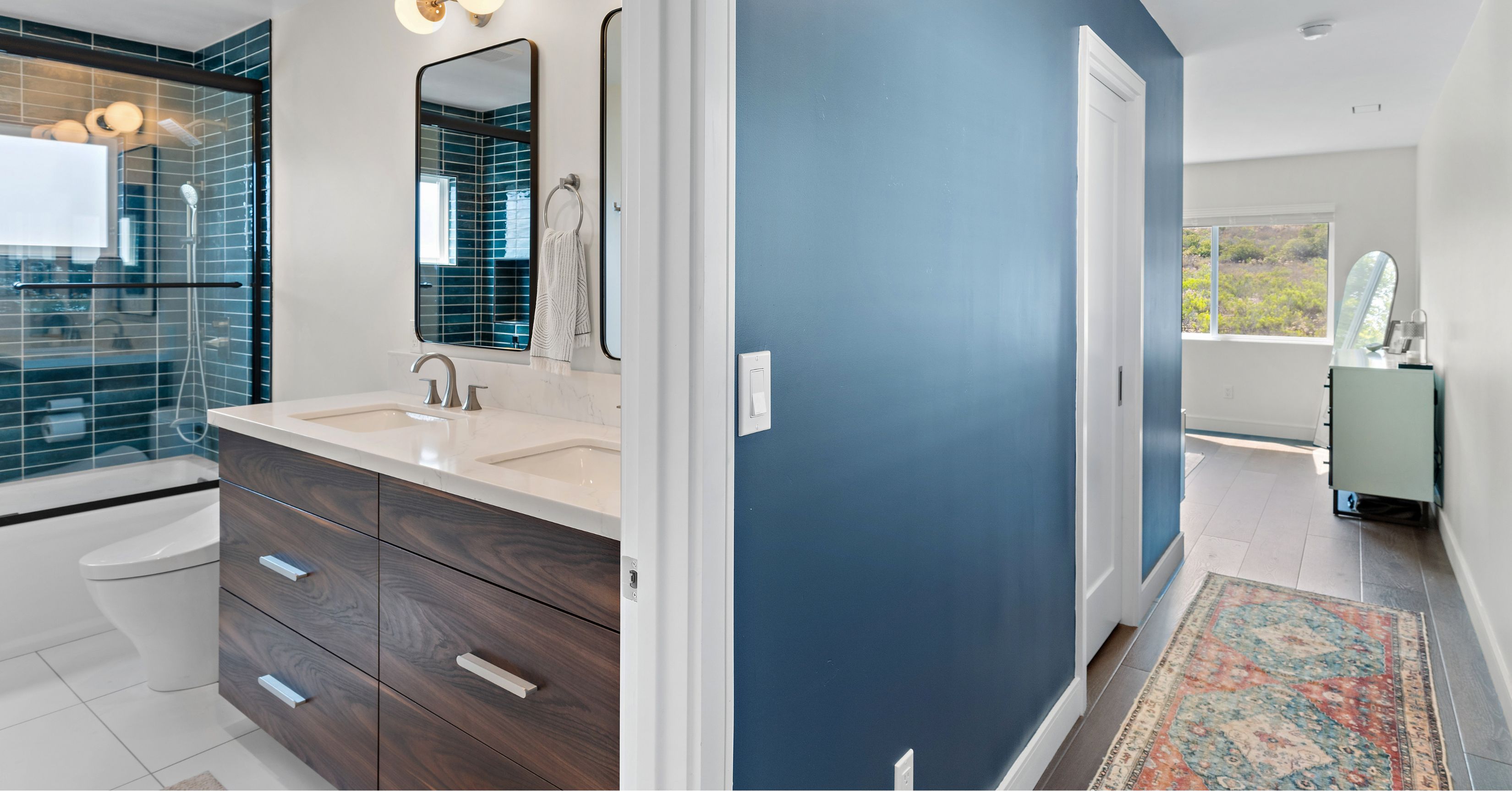 Modern bathroom addition with double vanity, walk-in shower featuring blue tile, and contemporary finishes connected to a newly expanded living space.