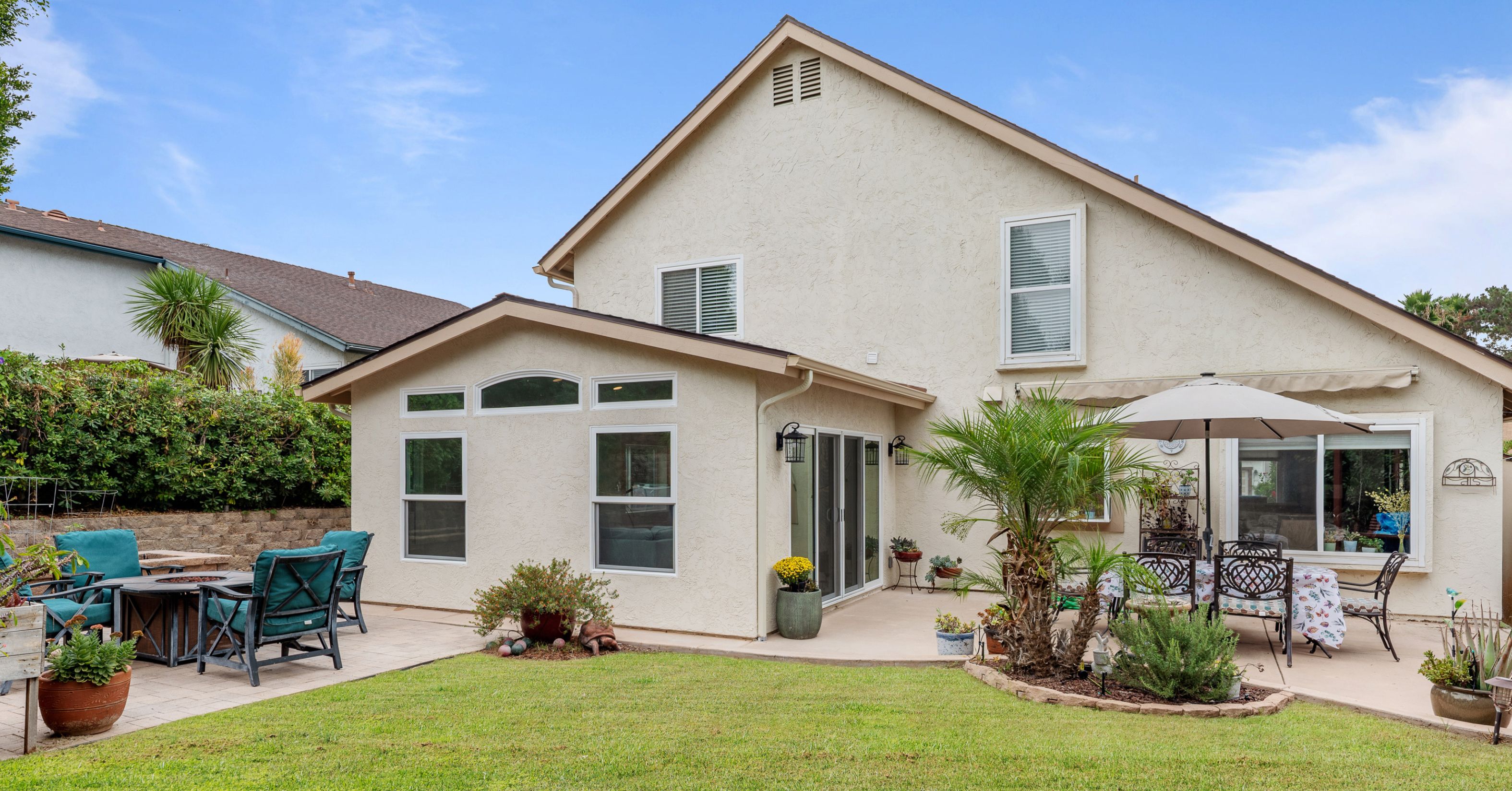 Rear view of a remodeled home with a single-story addition, large windows, and an accessible backyard patio designed for long-term living.