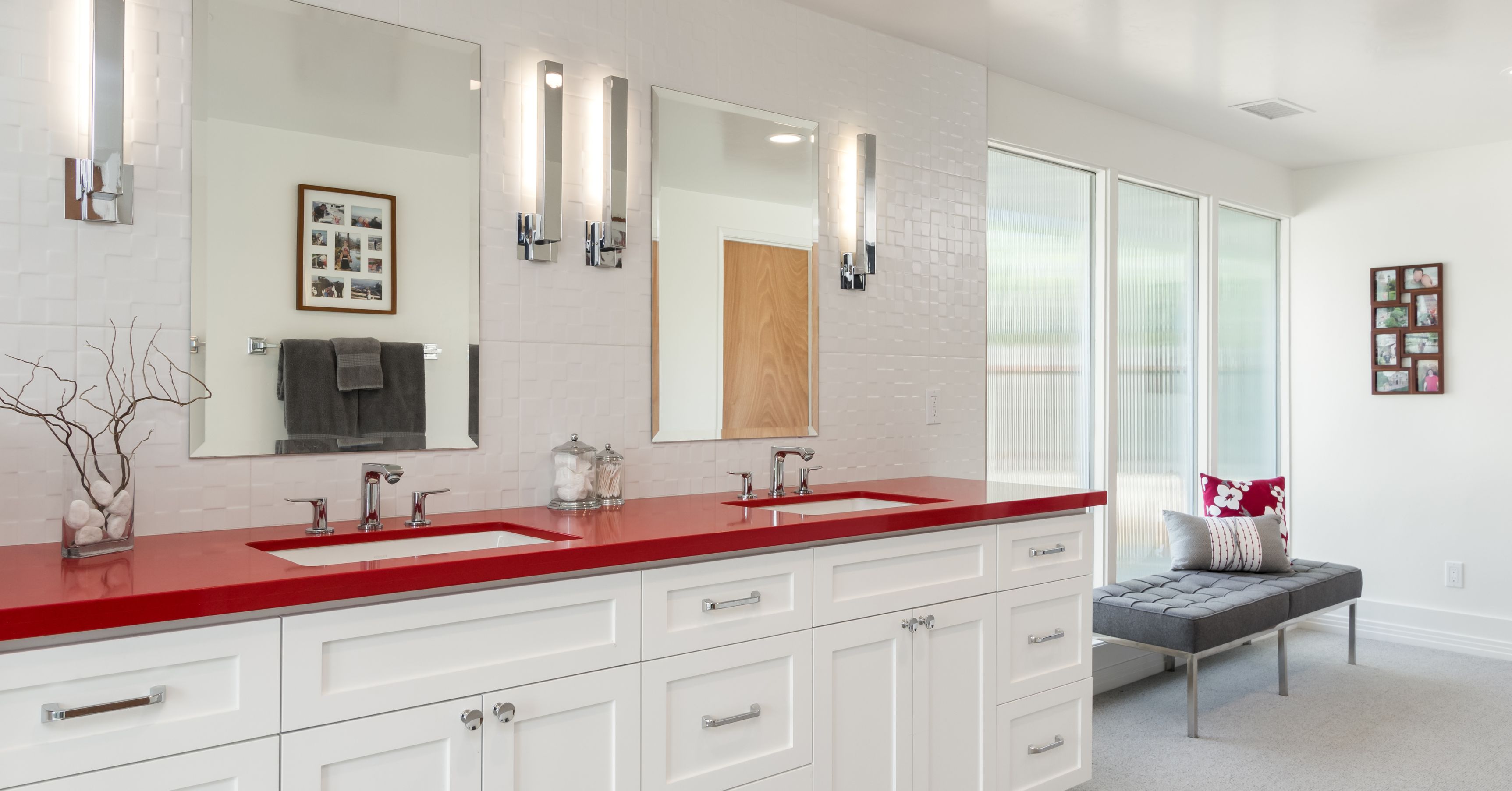 Modern bathroom with double vanity, white cabinetry, bold red countertops, large mirrors, and contemporary lighting.