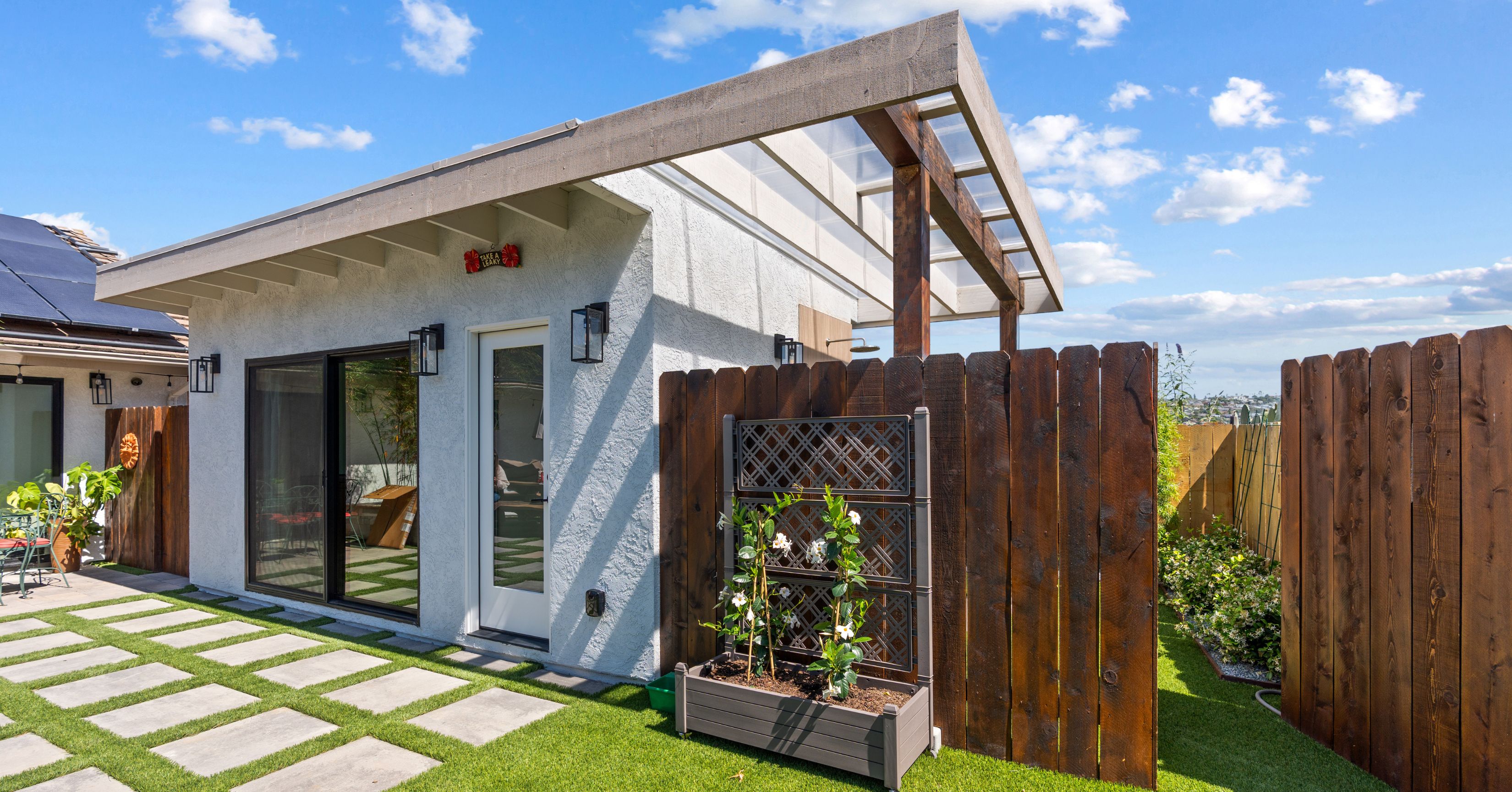 Detached accessory dwelling unit (ADU) with modern design, sliding glass doors, covered patio, and landscaped backyard.