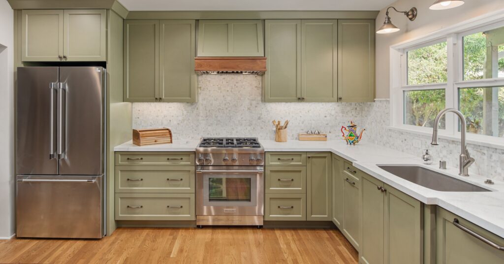 Spacious remodeled kitchen with sage green cabinetry, quartz countertops, stainless steel appliances, and large windows.