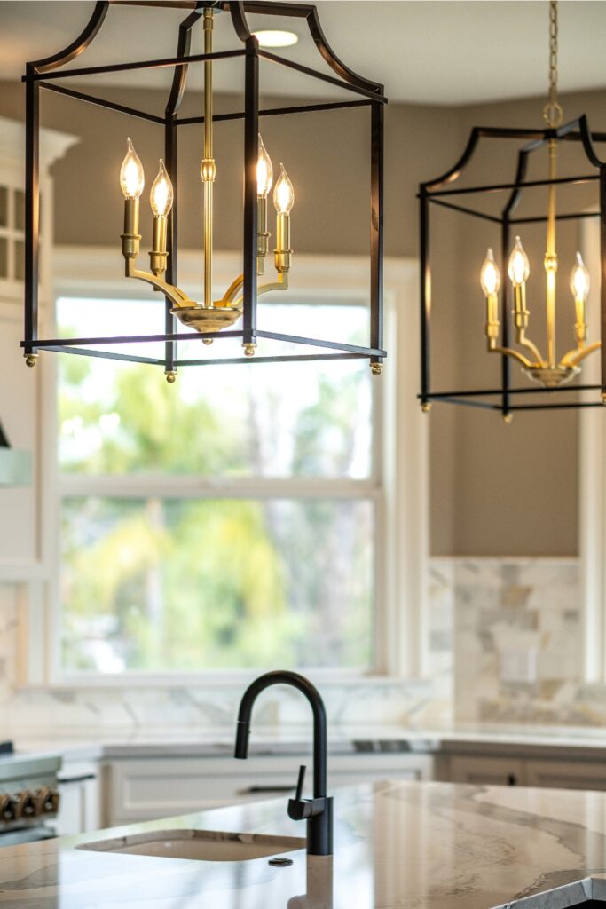 Black and brass lantern pendant lights suspended above the kitchen island and prep sink.