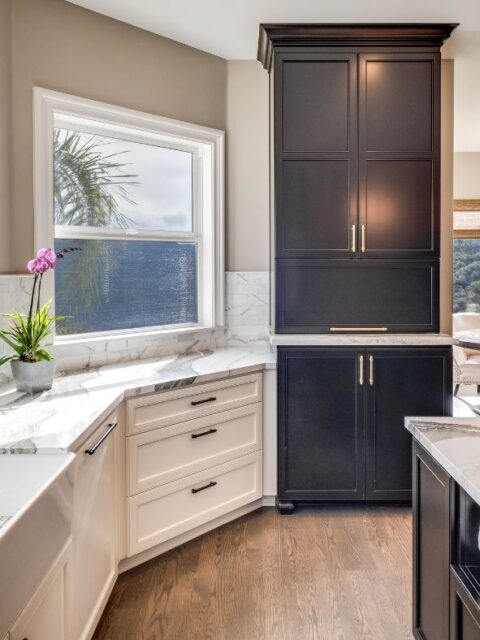 Alpine kitchen remodel with a black island, white perimeter cabinetry, professional range, stone countertops, and oversized lantern pendant lights.