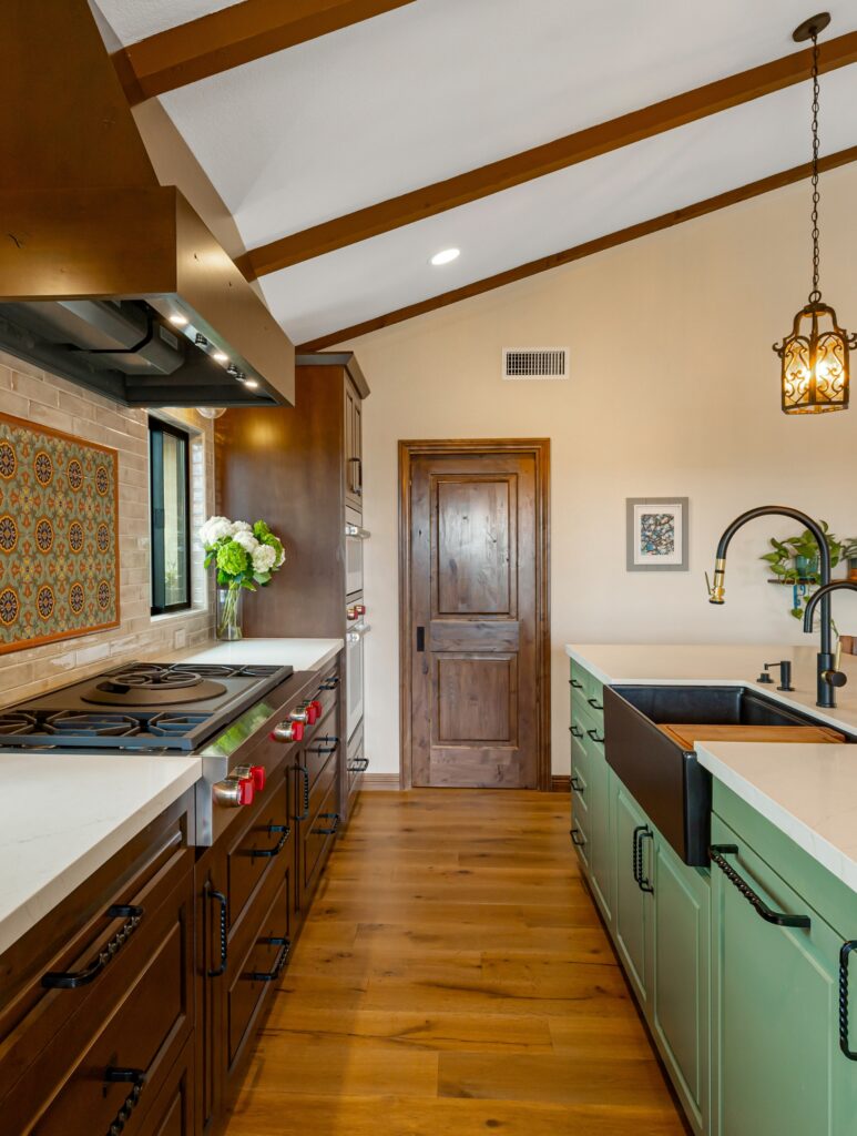 Vista kitchen remodel with vaulted wood-beam ceiling, green island, dark wood cabinetry, apron sink and professional range.