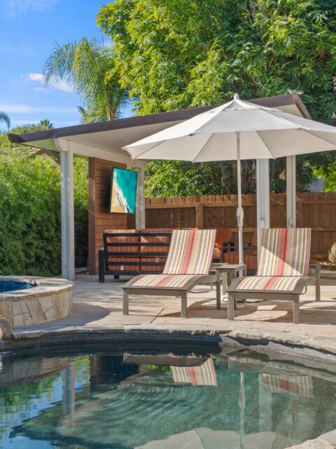 Bonita outdoor living remodel with pool, shaded lounge chairs, covered seating area, mounted TV and wood-look accent wall.