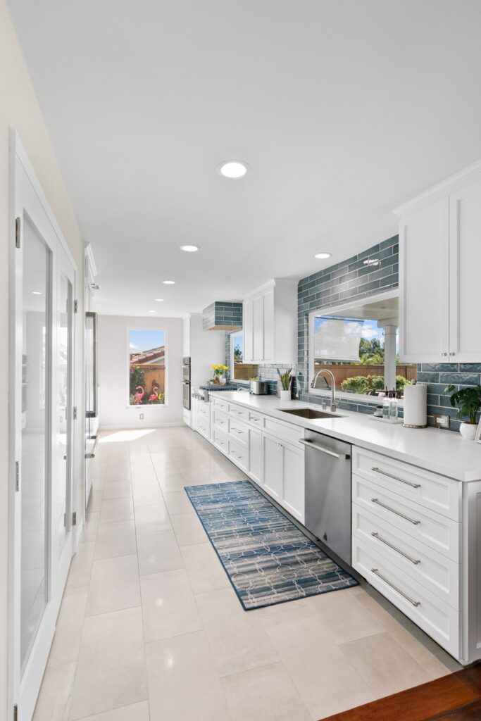 Bonita kitchen remodel with white Shaker cabinets, white counters, blue tile backsplash and stainless dishwasher.