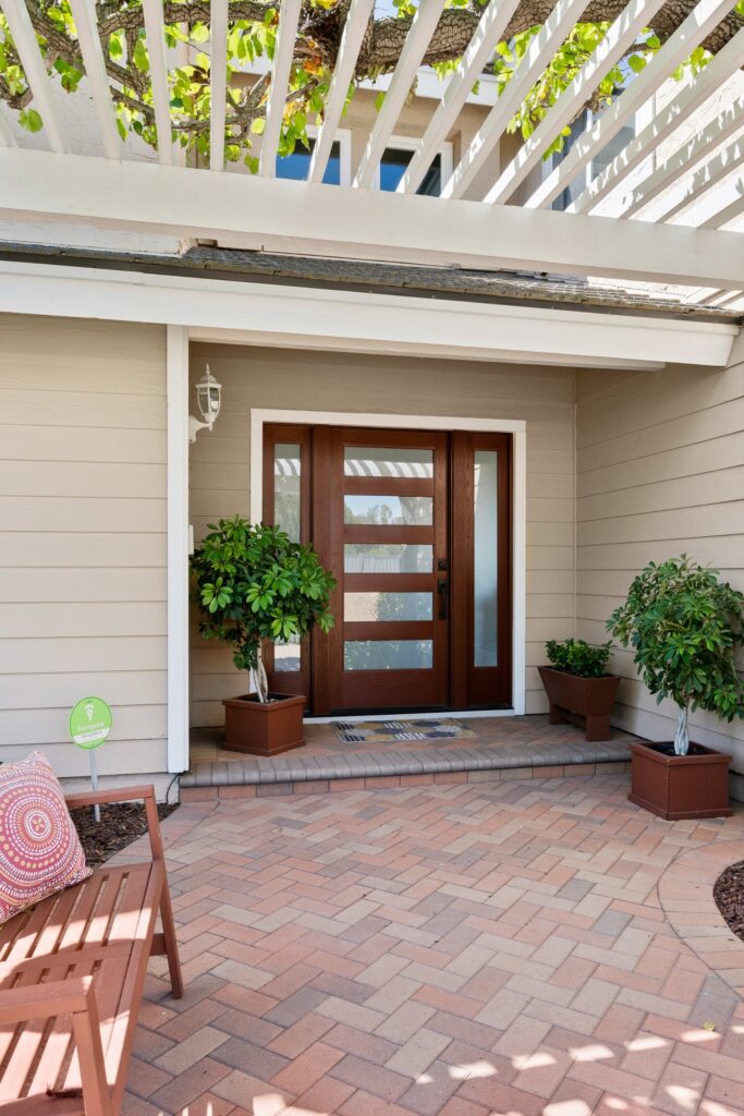 Front entry with a wood-and-glass door, narrow sidelights, brick pavers and an overhead pergola.