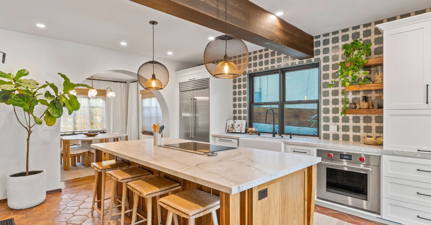 Remodeled kitchen with a marble-topped wood island, custom white cabinets, patterned tile walls, and professional appliances.