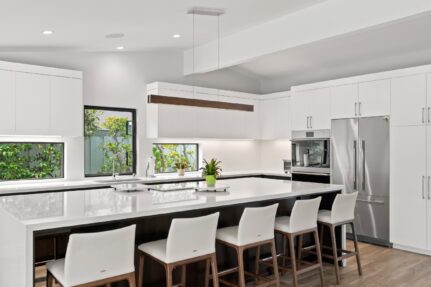 Bright San Diego kitchen remodel with white cabinetry, a dark wood island, stainless steel appliances, and seating for four.