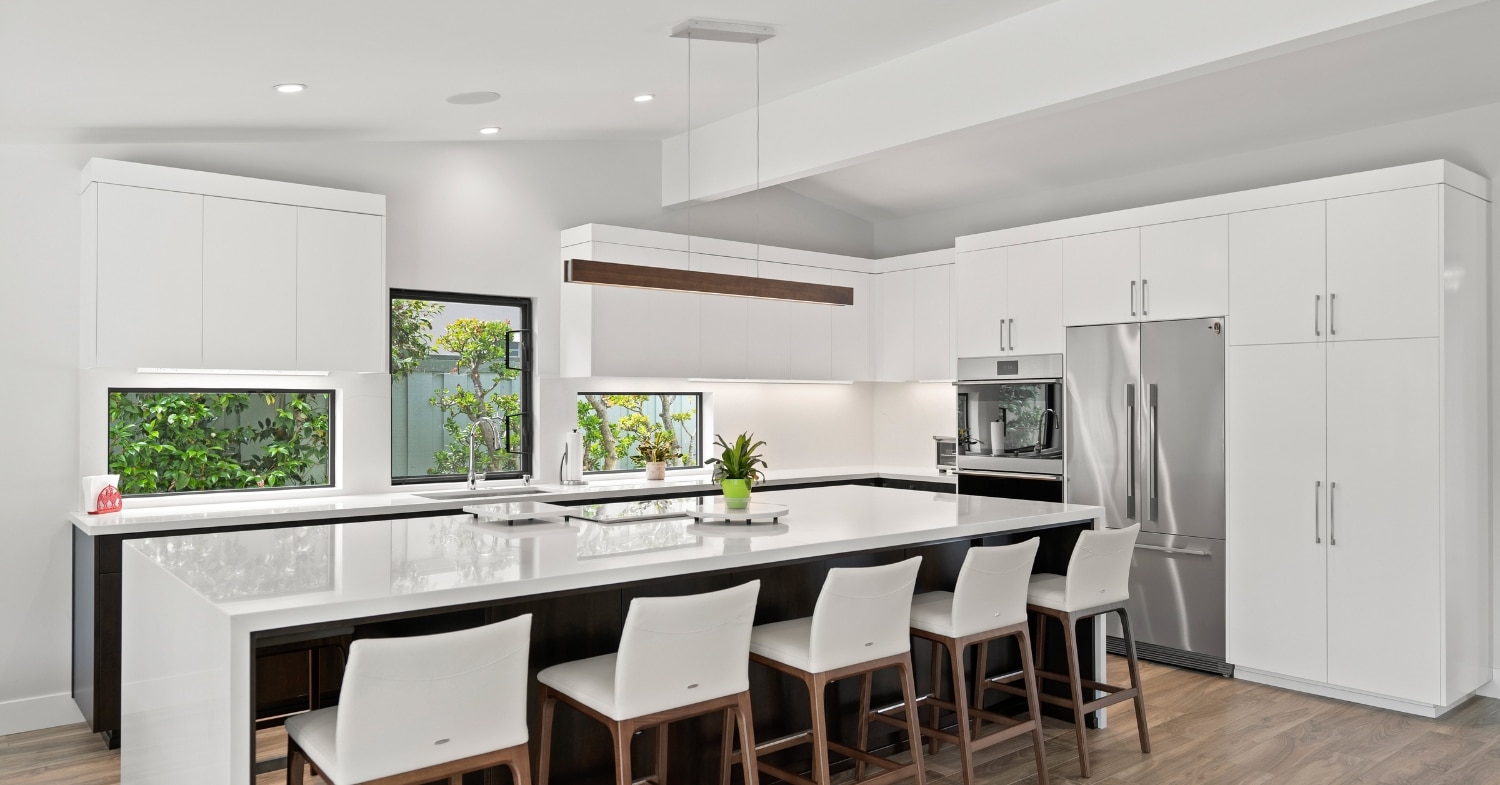 Bright San Diego kitchen remodel with white cabinetry, a dark wood island, stainless steel appliances, and seating for four.