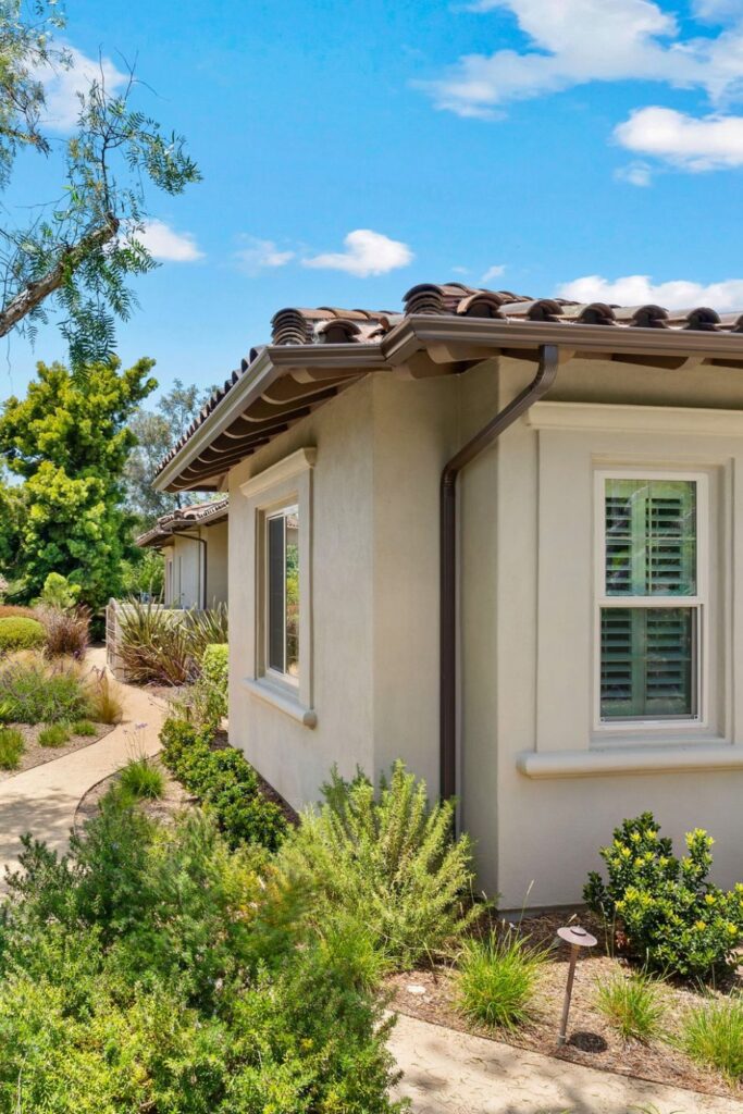 Exterior view of a Spanish-style Rancho Bernardo home addition beside drought-tolerant landscaping and a curved pathway.