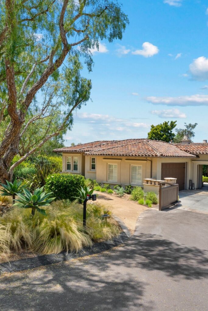 Front exterior of a Spanish-style Rancho Bernardo home with drought-tolerant landscaping and a decomposed-granite path.