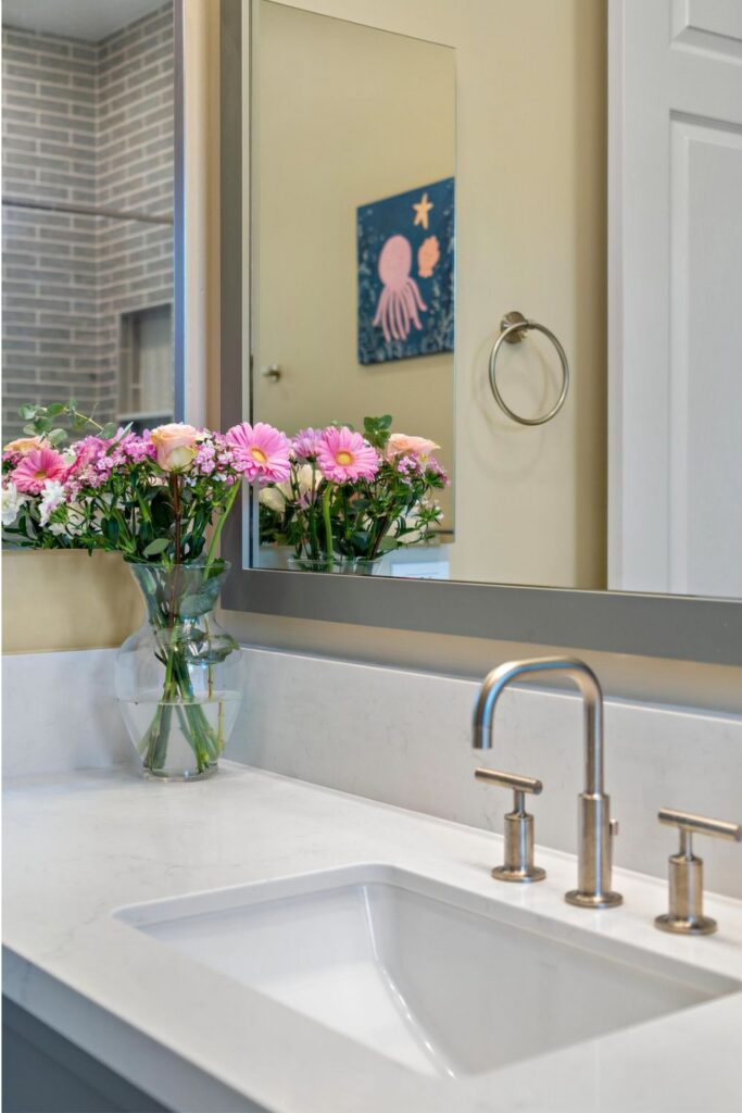 Bathroom vanity with white quartz countertop, undermount sink, brushed-nickel faucet, and large framed mirror.