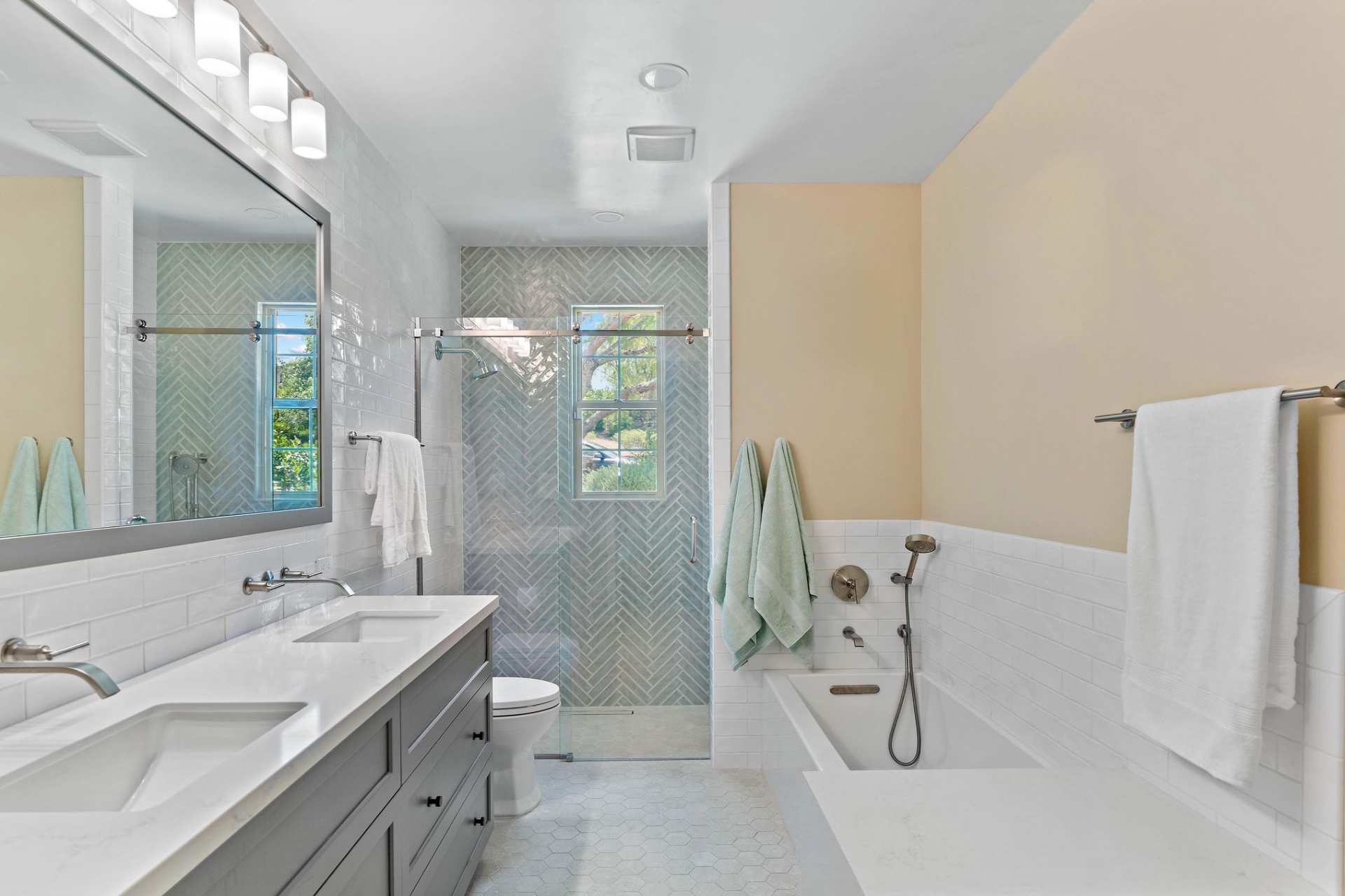 Remodeled Rancho Bernardo bathroom with double vanity, soaking tub, glass shower, herringbone tile, and hexagonal flooring.