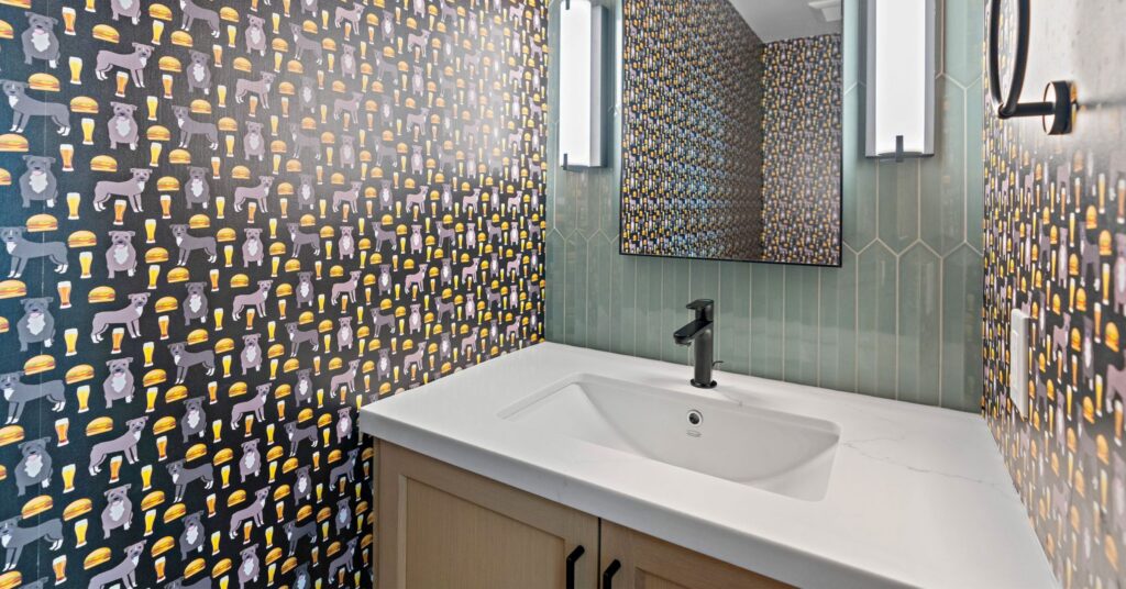 Designer powder room with custom wallpaper, green vertical tile accent wall, floating vanity, and modern black fixtures.