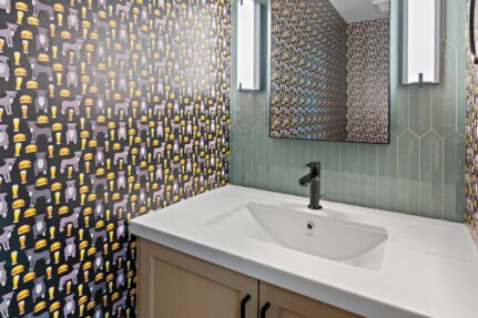 Designer powder room with custom wallpaper, green vertical tile accent wall, floating vanity, and modern black fixtures.