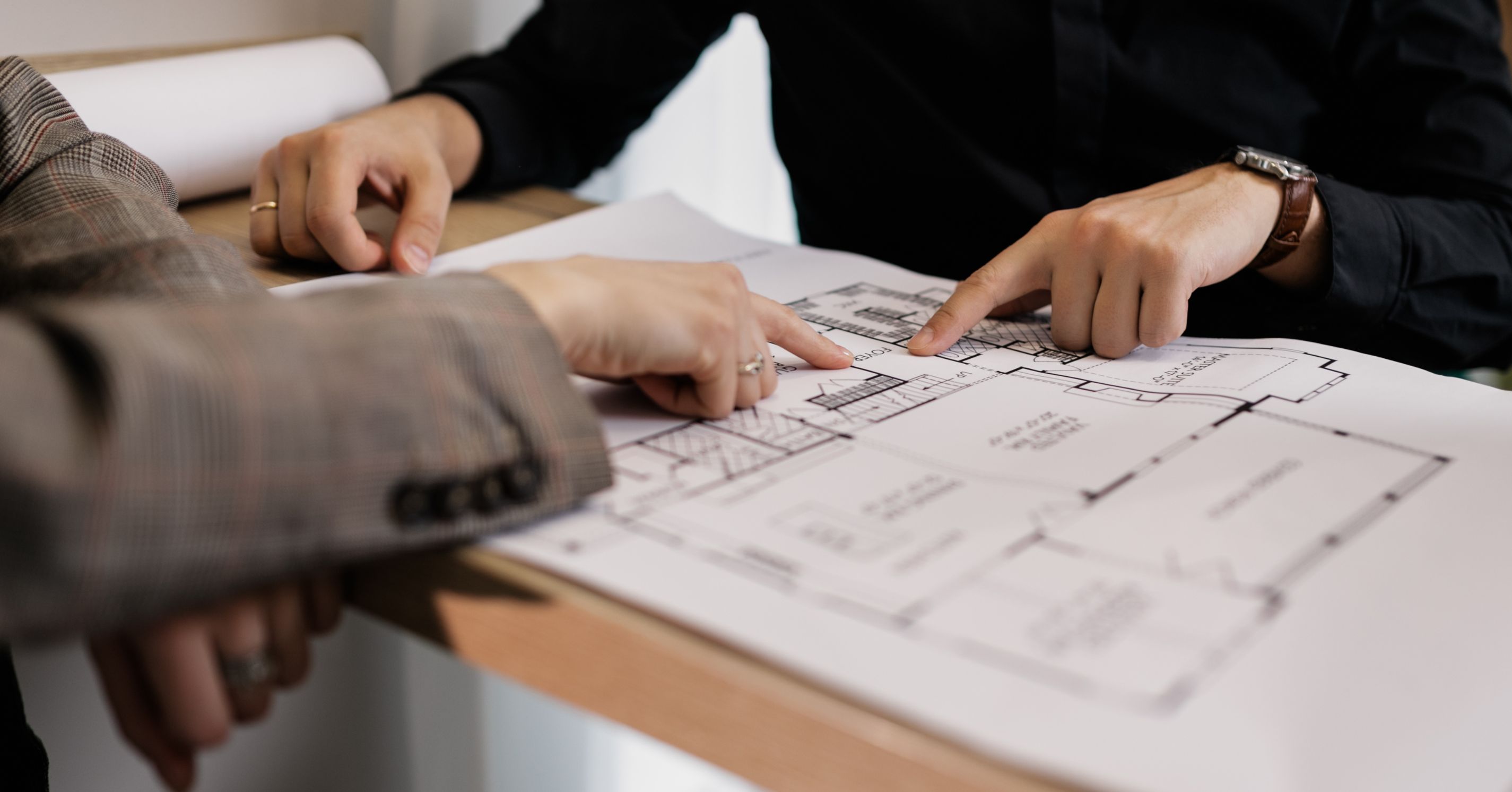 Homeowners and a remodeling professional reviewing architectural floor plans during the design and pre-construction planning phase.