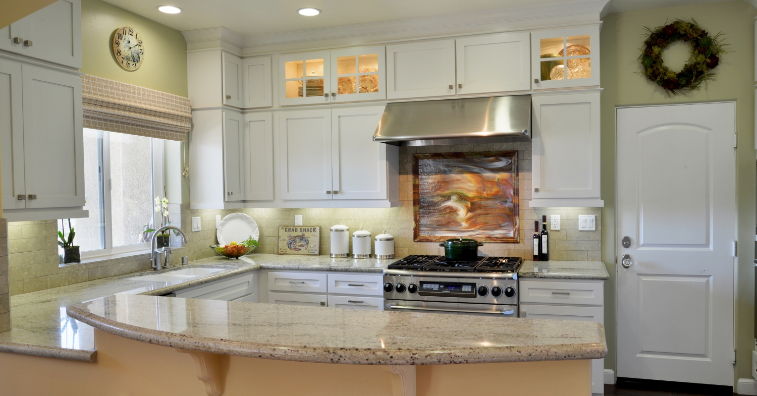 Traditional kitchen with white custom cabinetry, granite countertops, a large wood island, decorative lighting, and a built-in bar.