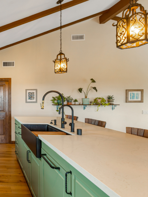 Large custom kitchen island with farmhouse sink, quartz countertops, and decorative pendant lighting.