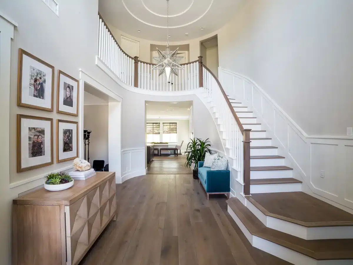 Two-story entry with a curved white staircase, dark stair treads and a gallery wall.
