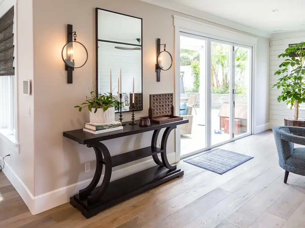 Interior entry with a dark console table, a tall mirror and glass doors looking onto a patio.