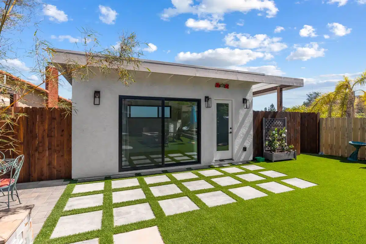 Backyard dwelling with sliding glass doors, lawn, and a paver patio.