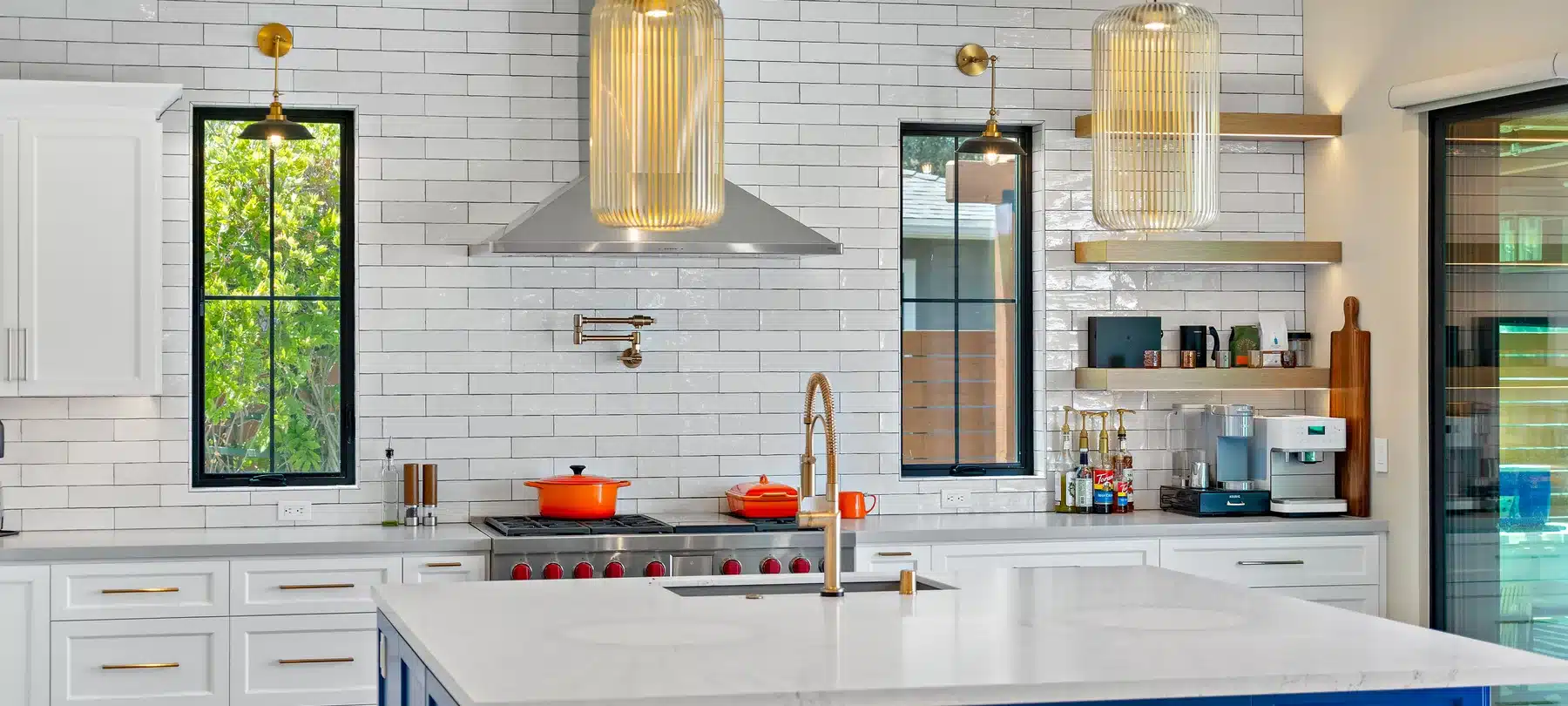 Kitchen with a blue island, white cabinetry, and woven pendant lights.
