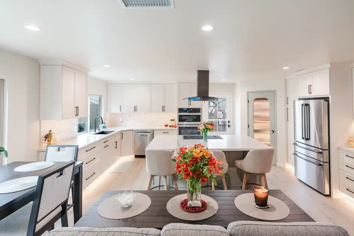 Kitchen and dining area with a cooktop island and white cabinetry.