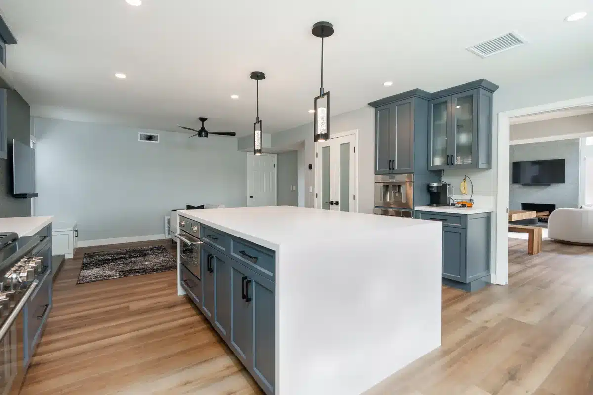 Kitchen with gray cabinetry and a white waterfall island.