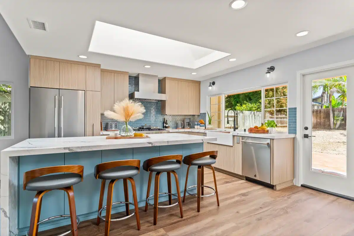 Kitchen with natural wood cabinetry, a blue island, and garden views.