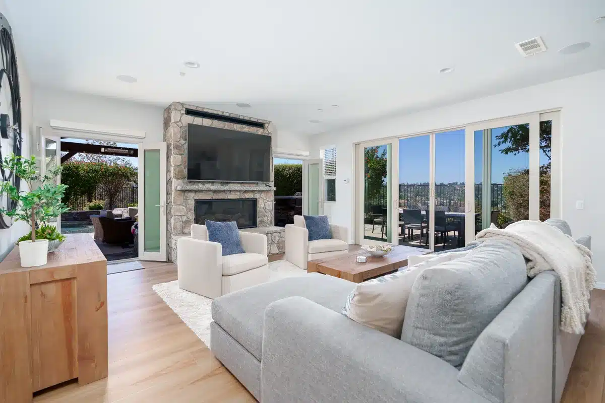 Living room with a stone fireplace and sliding doors opening to the patio.