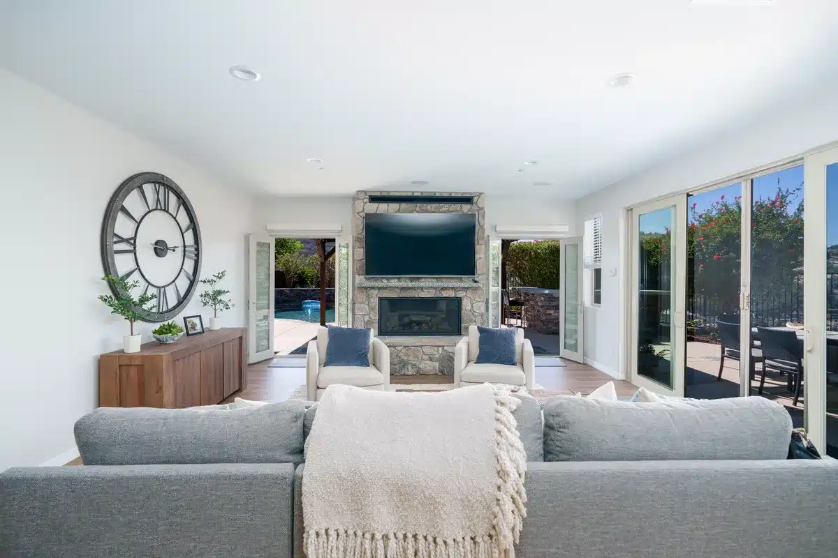 Bright living room with a stone fireplace and large garden-facing windows.