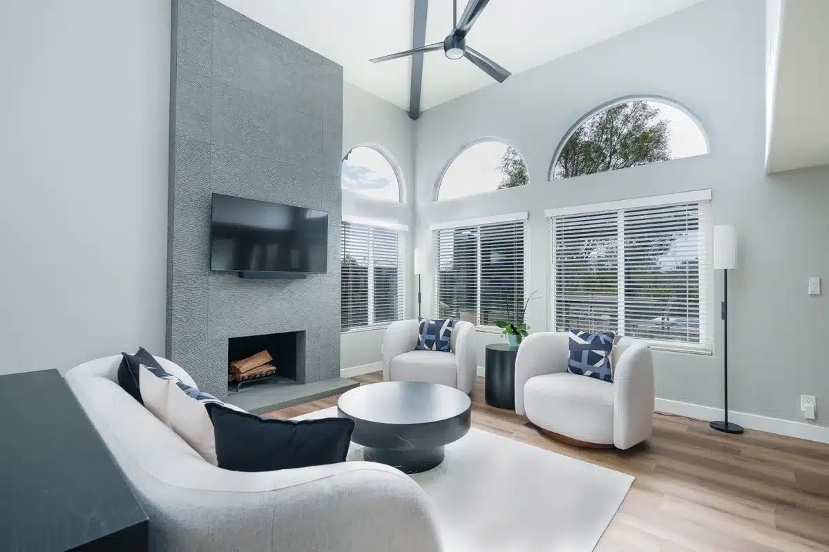 Living room with a vaulted ceiling, tall fireplace, and arched windows.