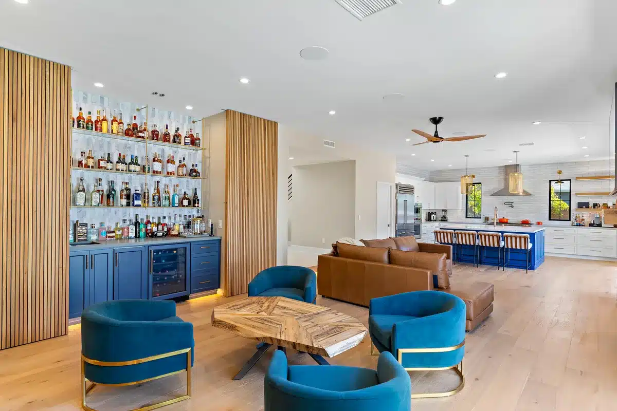Open living room and kitchen with a blue home bar and wood slat walls.