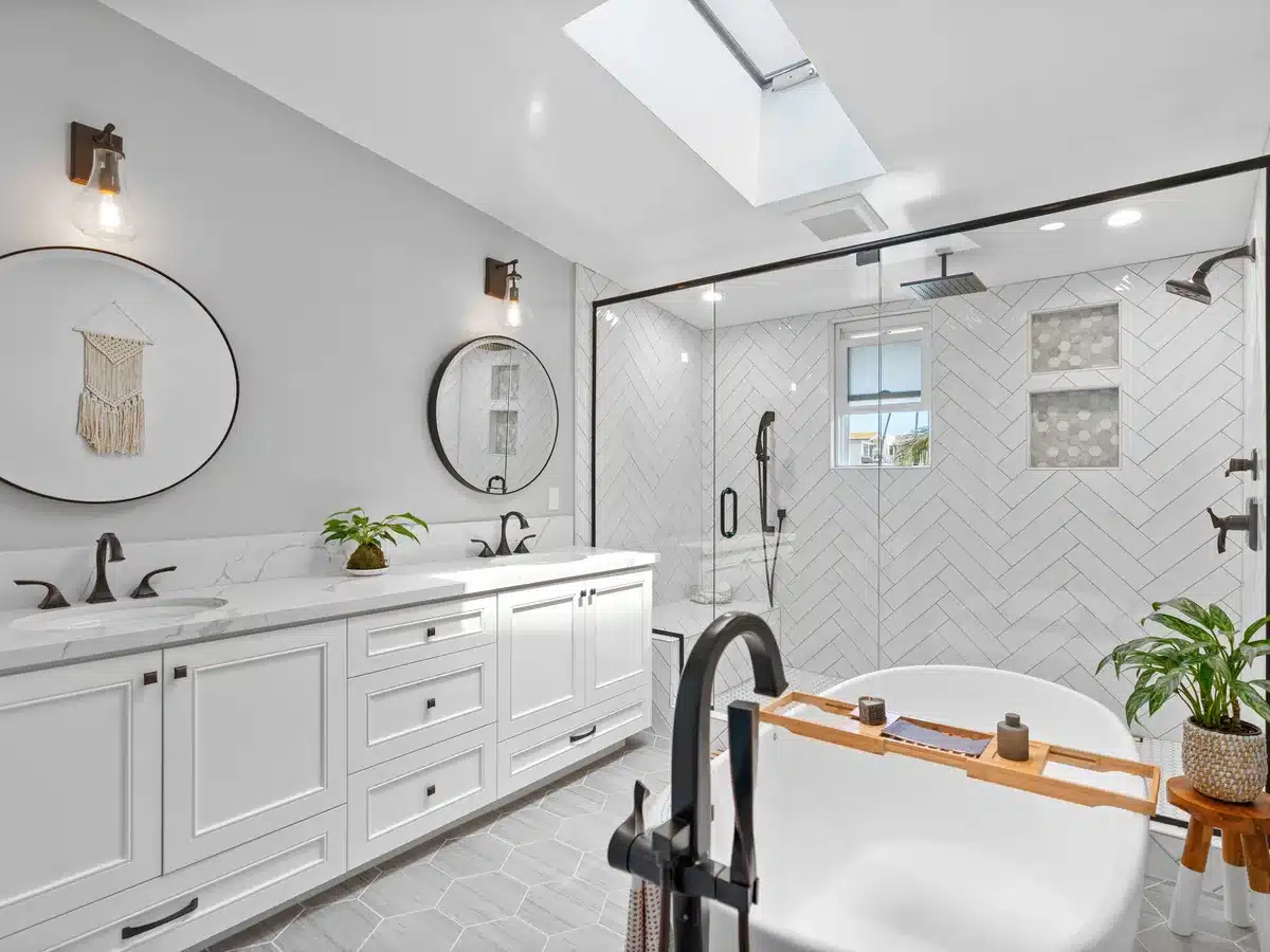 Bathroom with a freestanding tub, double vanity and glass-enclosed tile shower.