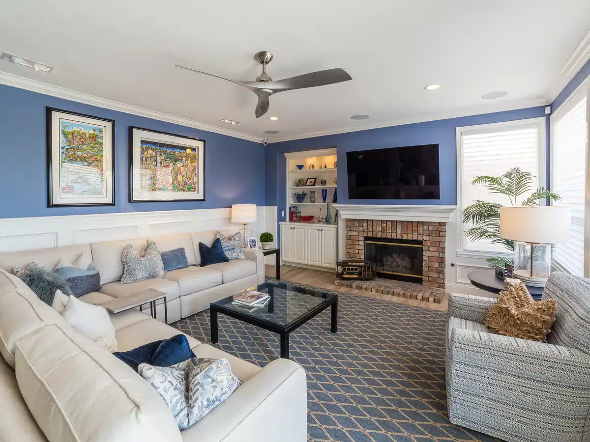 Family room with blue walls, a cream sectional sofa and a brick fireplace.