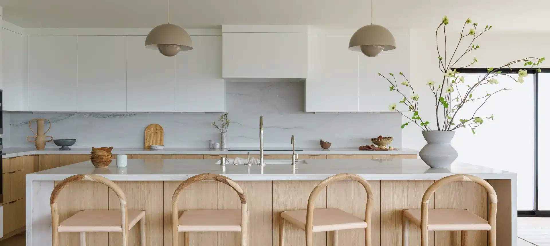 Kitchen with a light oak island, four curved wood stools and matching pendant lights.