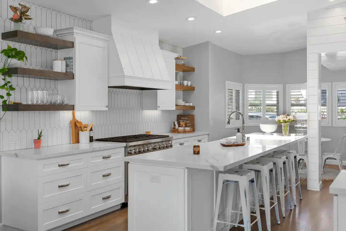 White kitchen cabinetry, open wood shelves, and an island in a La Jolla remodel.