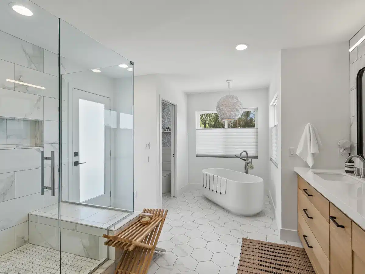 Bright bathroom with a glass-enclosed shower, freestanding tub, and wood vanity.