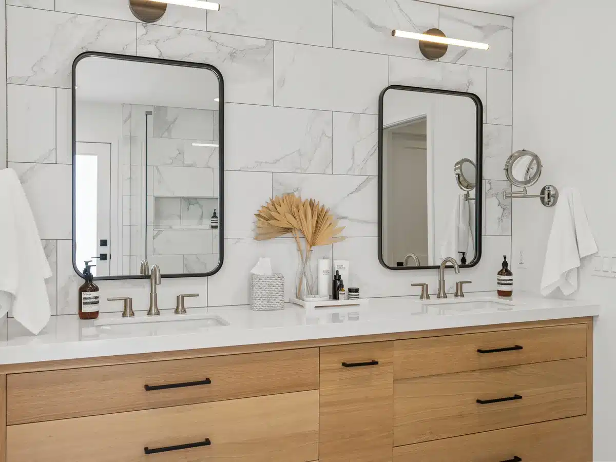 Wood double vanity with two black-framed mirrors and brass faucets.