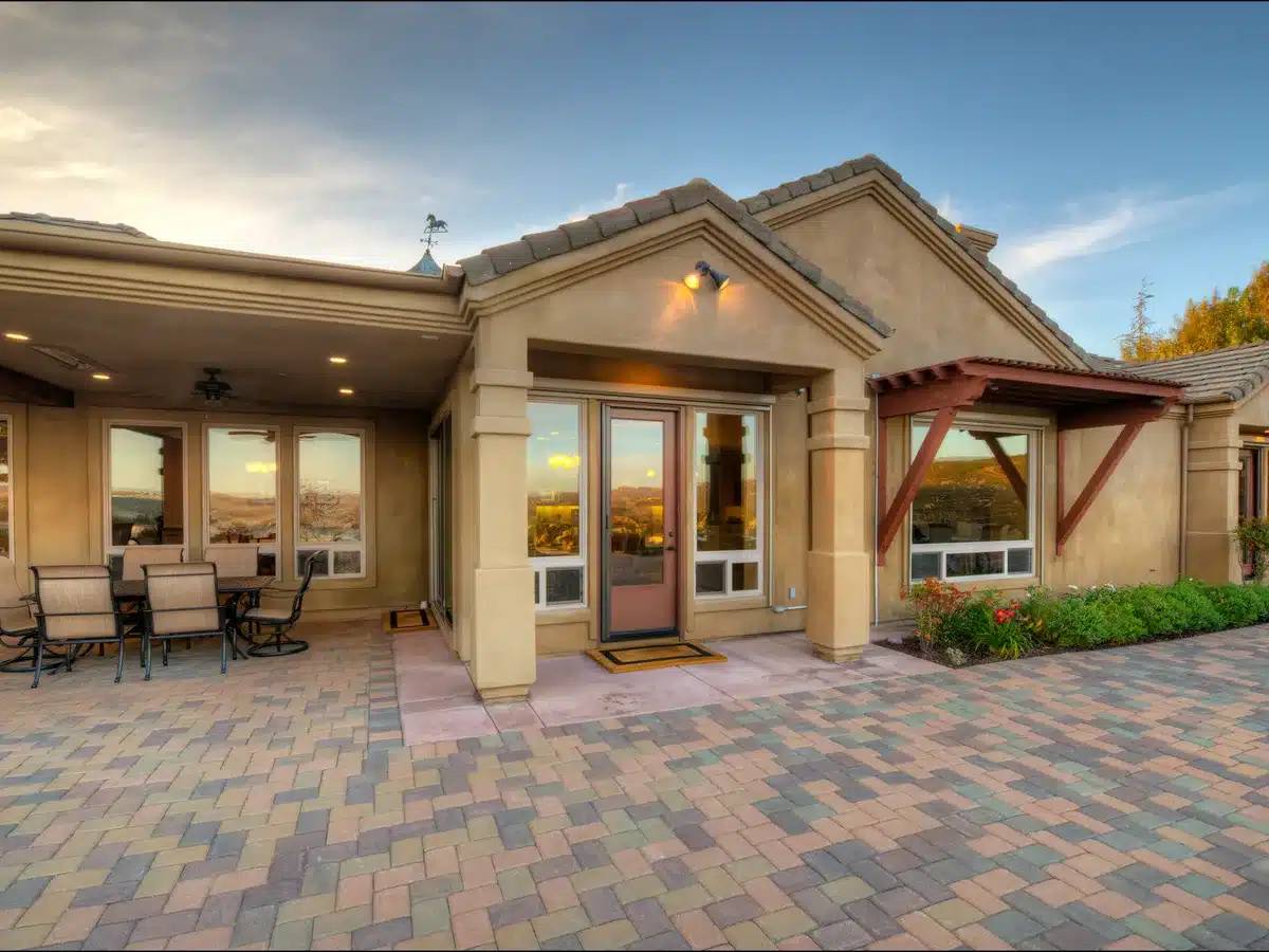 Covered backyard patio with a dining area, wood beams, and glass French doors.