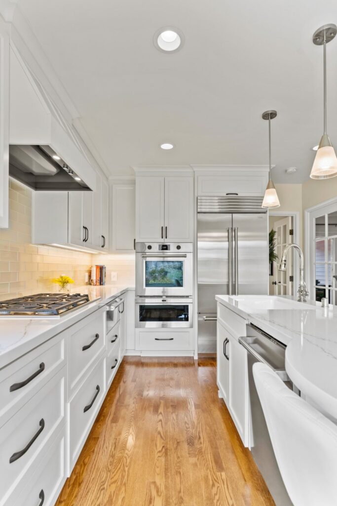 La Mesa kitchen remodel with white cabinetry, veined counters, peninsula seating, pendant lights and stainless appliances.